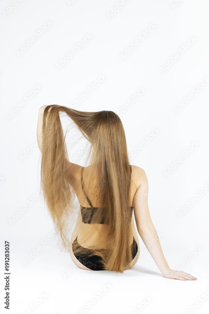 Obraz premium fashion studio photo of beautiful young woman showher luxurious long hair, natural color, back view, arms