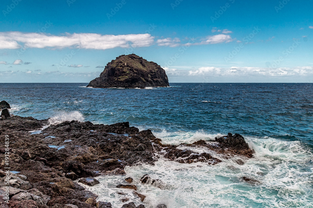Ein Blick aufs Meer mit einem großen Felsen im Hintergrund und spritzendem Wasser bzw. Gischt Ein Blick aufs Meer mit einem großen Felsen im Hintergrund und spritzendem Wasser bzw. Gischt