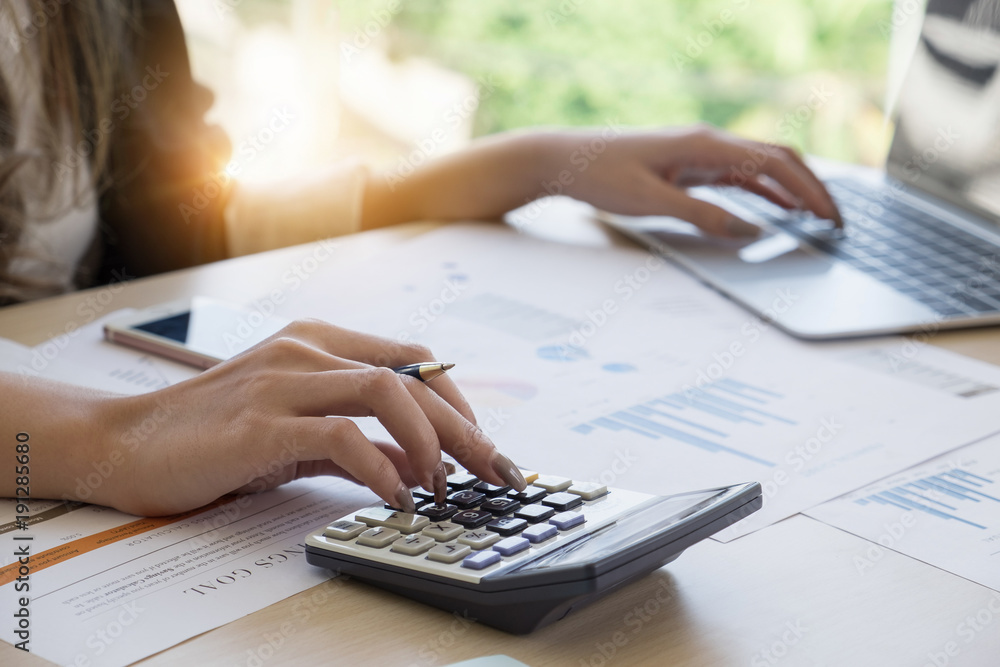 Close up Business woman using calculator and laptop for do math finance on  wooden desk in office and business working background, tax, accounting,  statistics and analytic research concept Stock Photo | Adobe