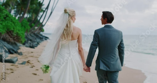Bride and groom walking down the beach at sunset