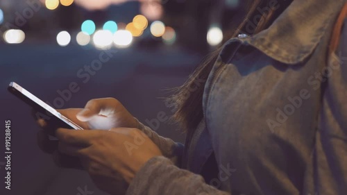 Female hands using smart phone touch screen at night at the street