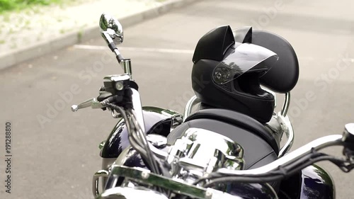 Close-up of a motorcycle on an empty road in the city. On the motorcycle lies is a protective helmet with cat's ears. Girl biker and her motorcycle on an empty road in the countryside.