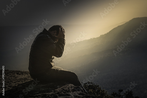 Photography The desperate young man sat on the edge of the cliff
