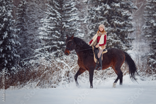 Rider young girl rides brown horse through winter fore