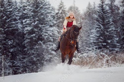 Close-up of girl rider riding gallop on horse through winter forest. Racing in snow.
