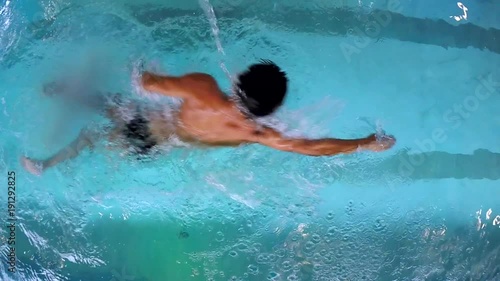 Young Man Crawl Swimming in the Pool/Young man crawl swomming in the pool. The camera is just above his head. Swiiming is the way to stay fit photo