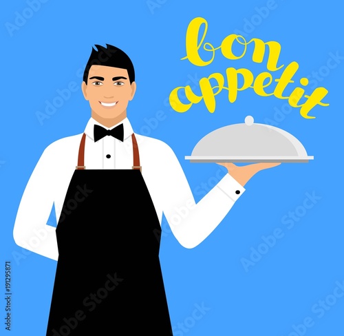 a young smiling waiter in uniform holds a tray