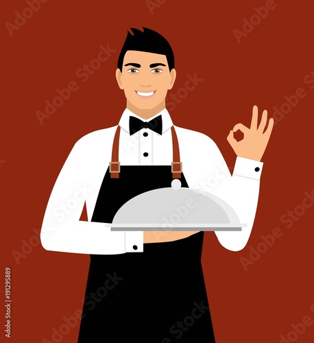 a young smiling waiter in uniform holds a tray and shows a sign okay