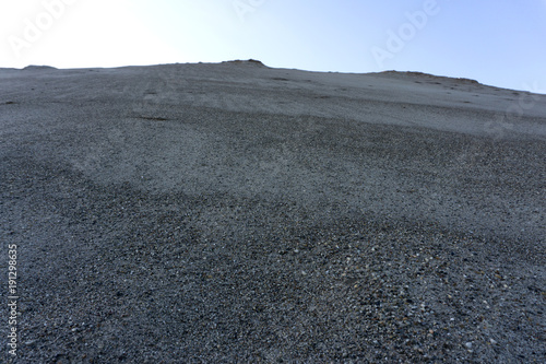 Sandy mountain against the sky rises up .