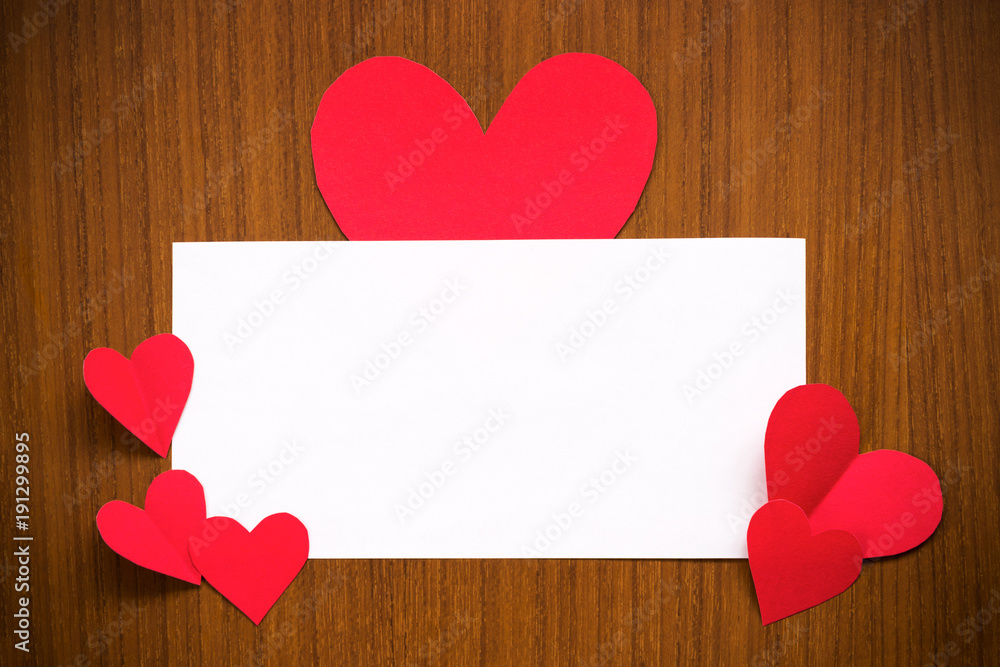 White paper empty or blank card for text, message, wordings insertion decorating with big red hearts paper on the edge over dark brown teakwood background for love Valentine's day or wedding party