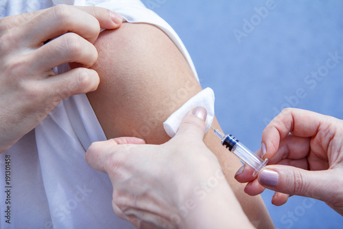 Doctor holding syringe for vaccination to upper arm of patient © Vitalii M