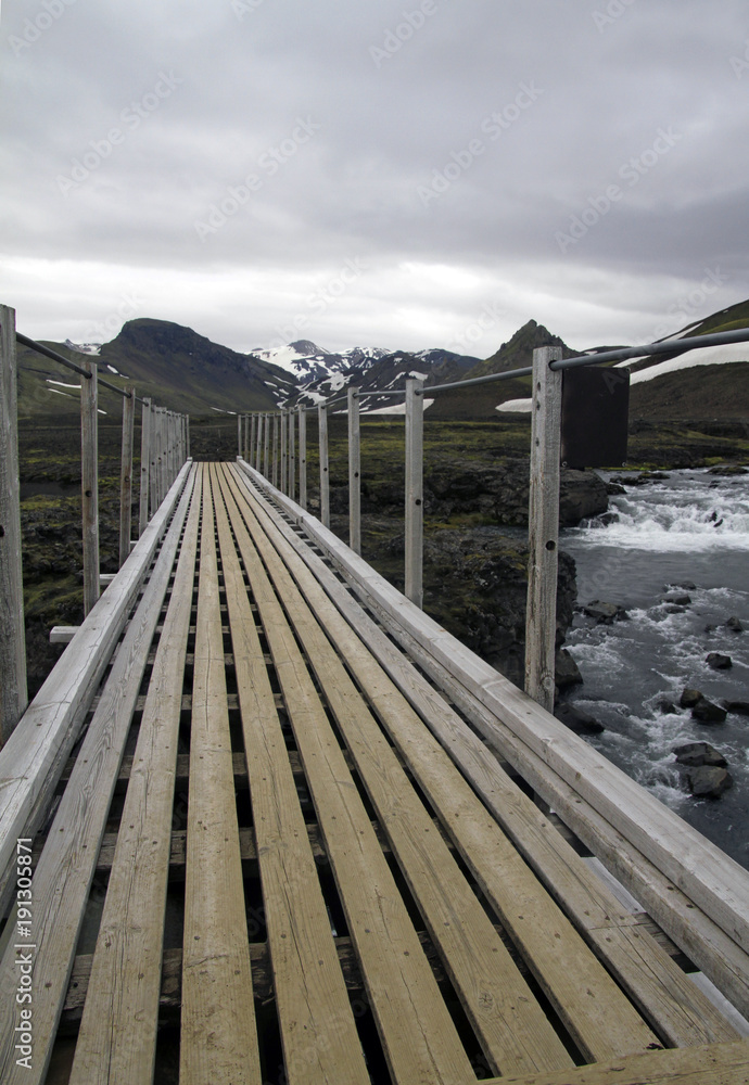 Obraz premium Wooden bridge over a mountain river in Iceland