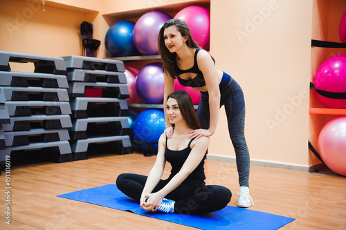 Instructor helping young girl doing stretching. Women doing stretching. Healthy lifestyle.