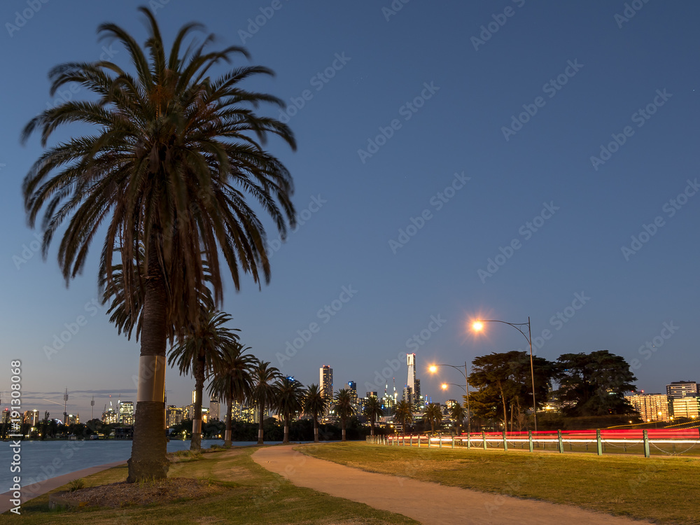 Light trails around Albert Park lake with the Melbourne skyline in the background.