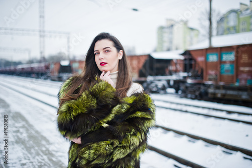 Brunette girl in green fur coat on the platform station at winter day. © AS Photo Family