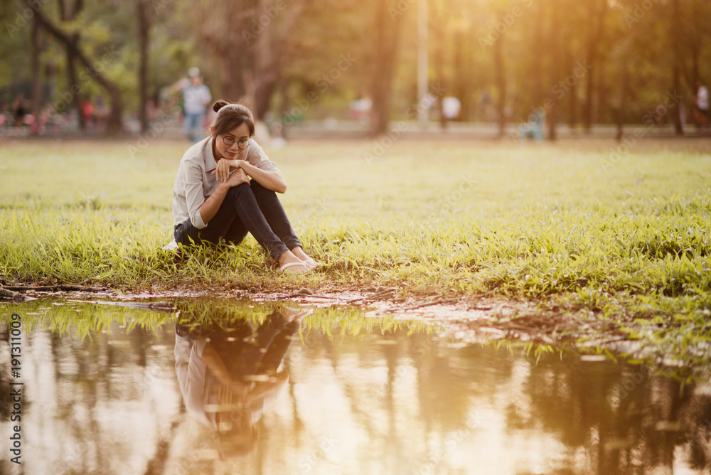 Asian woman sitting near swamp in the park.
