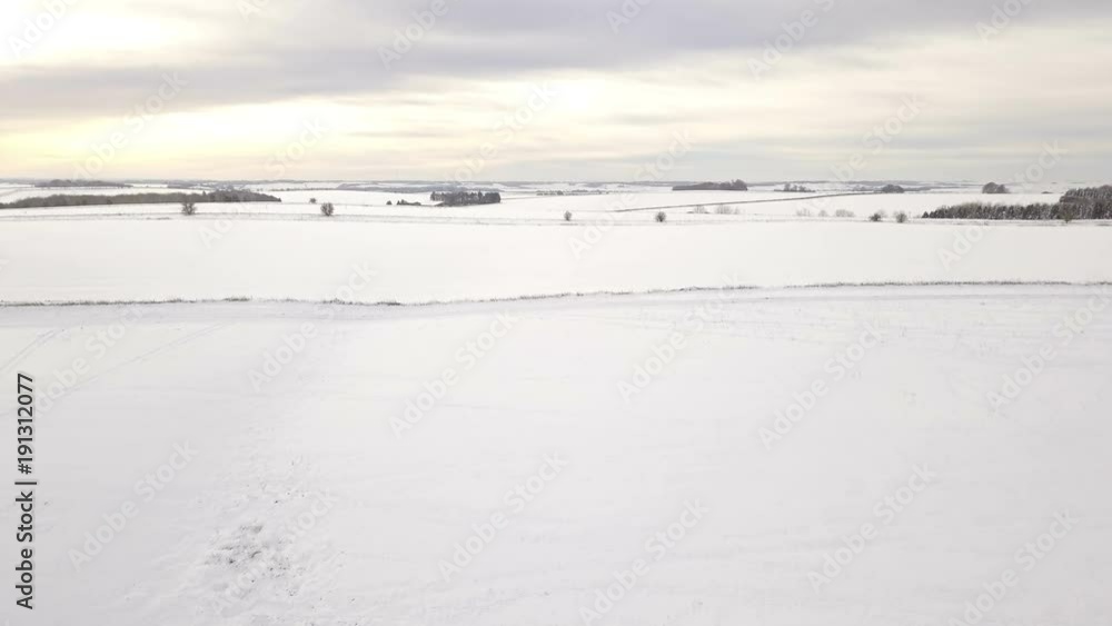 Flying over snow covered hills and farmland in winter into the setting sun Flying over snow covered hills and farmland in winter into the setting sun