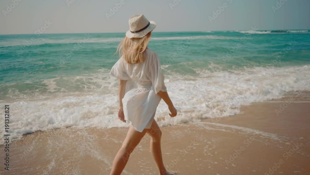 Woman walking on the ocean beach under blue sky in sunny day. Seascape view with palms. Woman walking on the ocean beach under blue sky in sunny day. Seascape view with palms.