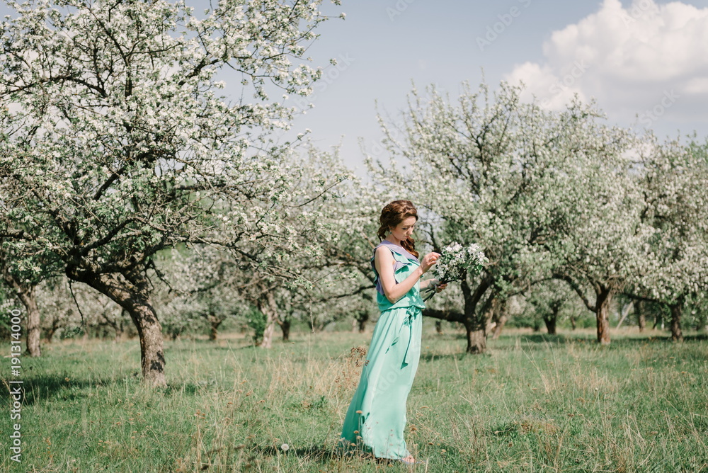 Girl in spring in a flowering apple orchard among apple trees with twigs of apple trees in hands Girl in spring in a flowering apple orchard among apple trees with twigs of apple trees in hands