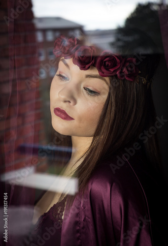 The dreamer.Beautiful girl in elegant pyjama standing near window  photo