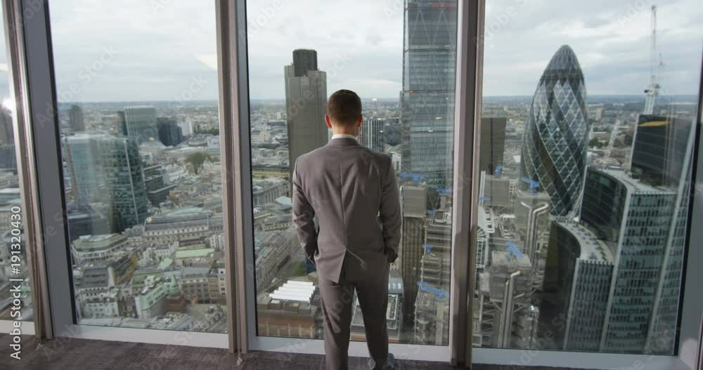 4K View from behind of young successful business executive looking out at view of the city. View from the window shows famous London skyline with iconic buildings. Slow motion 4K View from behind of young successful business executive looking out at view of the city. View from the window shows famous London skyline with iconic buildings. Slow motion