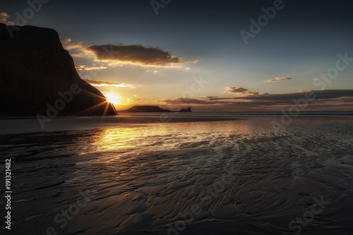 Sunset and wet sand at Worms Head  Worms Head  an iconic piece of land jutting out from Rhossili Bay on the Gower peninsula  South Wales  UK