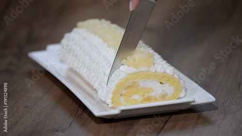 To cut with a knife a piece of sweet pineapple roll cake photo