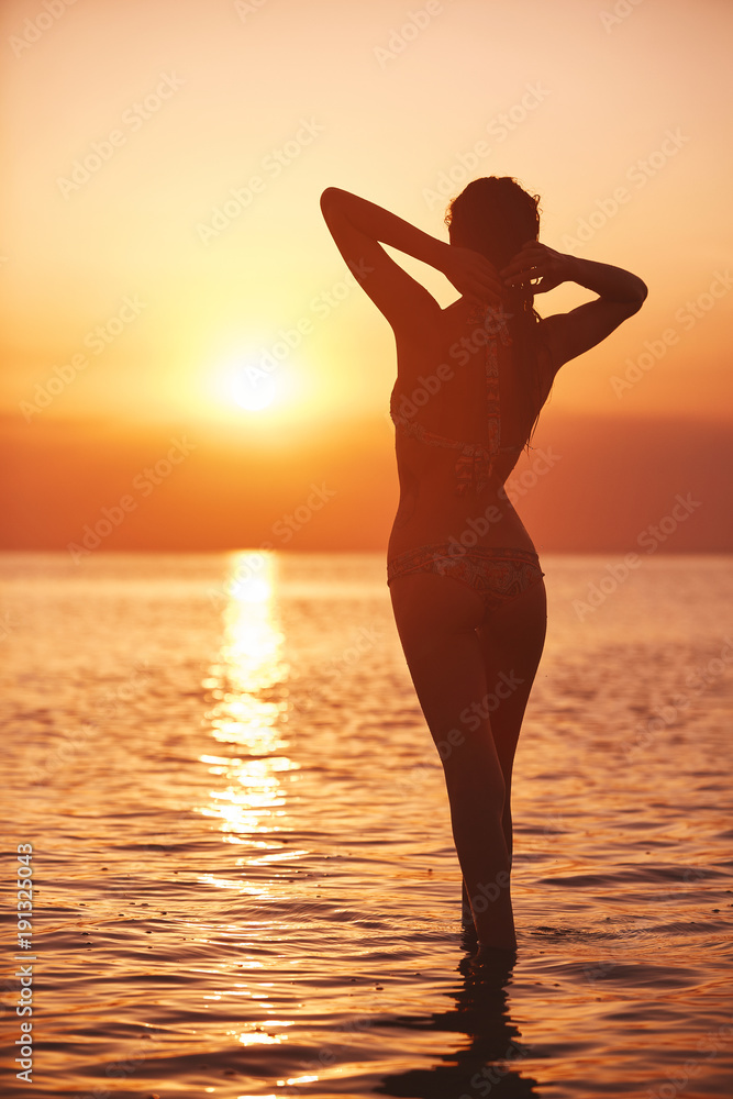 silhouette of a beautiful sexual girl against the sea and sunset. happy woman enjoying summer vacation