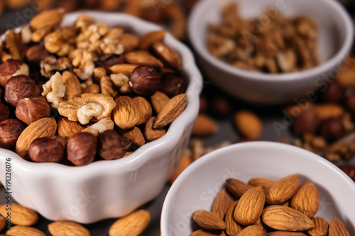 Three white cups filled with nuts, almonds, hazelnuts, walnut and.