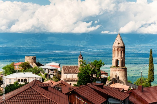 Wallpaper Mural Old houses with brown tile roofs, church of St. George in city of love - Sighnaghi, Kakheti, Georgia. Beautiful view on Alazani valley. Sunny day with blue sky with clouds. Torontodigital.ca
