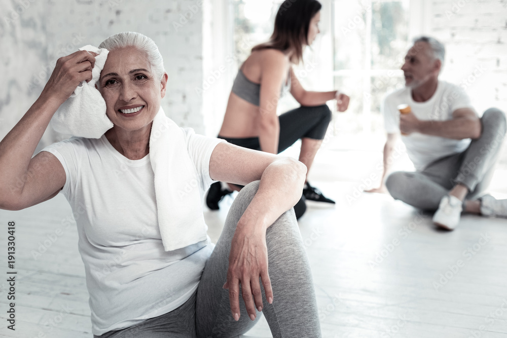 Nothing stops me. Extremely happy retired lady looking into vacancy with a cheerful smile on her face while resting after a training session at a gym. Nothing stops me. Extremely happy retired lady looking into vacancy with a cheerful smile on her face while resting after a training session at a gym.