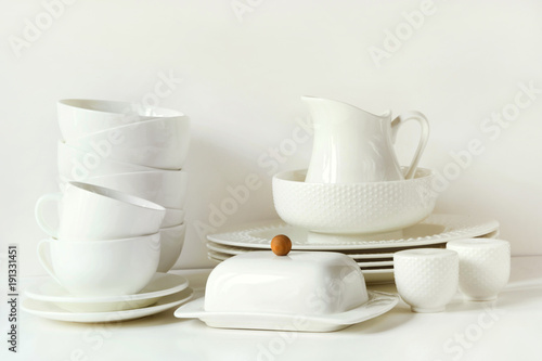 White tableware for serving. Crockery,dish, utensils and other different white stuff on white table-top. Kitchen still life as background. Copy space.