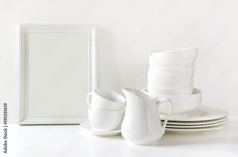White tableware for serving. Crockery,dish, utensils and other different white stuff on white table-top. Kitchen still life as background. Copy space. White tableware for serving. Crockery,dish, utensils and other different white stuff on white table-top. Kitchen still life as background. Copy space.