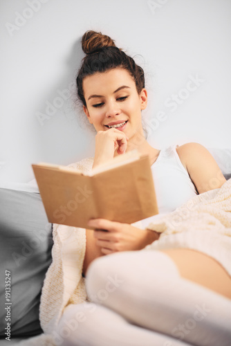 Girl reading book while sitting on the bed in the morning © chika_milan