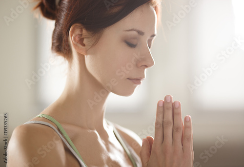 Relaxed young sportswoman doing yoga and meditating in studio