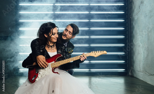 Wedding in the style of rock. Rocker or Biker wedding. Guys with stylish leather jackets. It's a rock'n'roll baby! Sweet couple in a photo studio. Steep shooting with electric guitar and smoke.