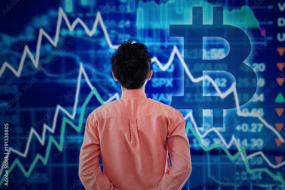 Male entrepreneur with declining graph and bitcoin symbol Male entrepreneur with declining graph and bitcoin symbol