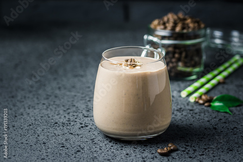 Mocha banana coffee breakfast smoothie and coffee beans in glass jar on dark concrete background. Selective focus, space for text.  photo