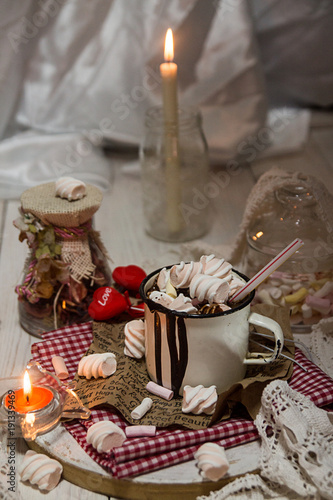 Mug of hot chocolate drink with marshmallow candies on top and candles on white background. Valentin's day love concept.