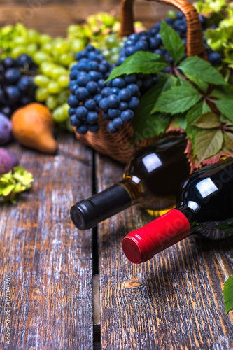 Red wine in a bottle and in the glass, cork, bottle screw and a set of products - cheese, grapes, nuts, pears,flowers, figs,white bread, baguette on a wooden board, background