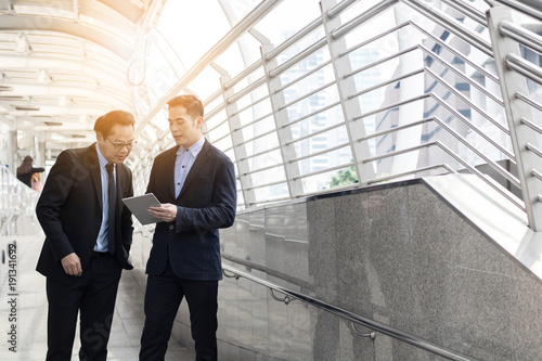 Businessman presenting work to boss, leader about planning project by laptop outside building.