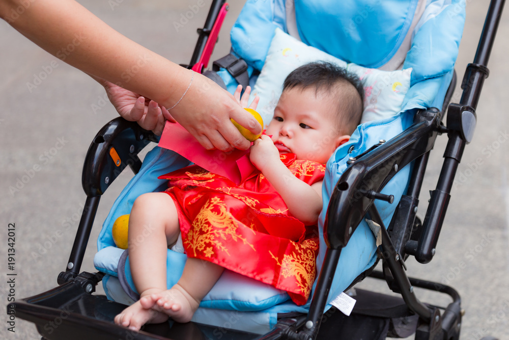 Close up of Chinese baby receiving reward and oranges, Chinese traditional in Chinese new year for Lucky, from parent in perambulator baby stroller.. Close up of Chinese baby receiving reward and oranges, Chinese traditional in Chinese new year for Lucky, from parent in perambulator baby stroller..