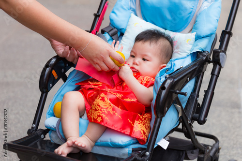 Close up of Chinese baby receiving reward and oranges, Chinese traditional in Chinese new year for Lucky, from parent in perambulator baby stroller..