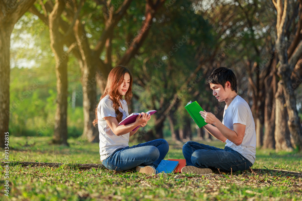 man and woman sitting and reading a book in park man and woman sitting and reading a book in park