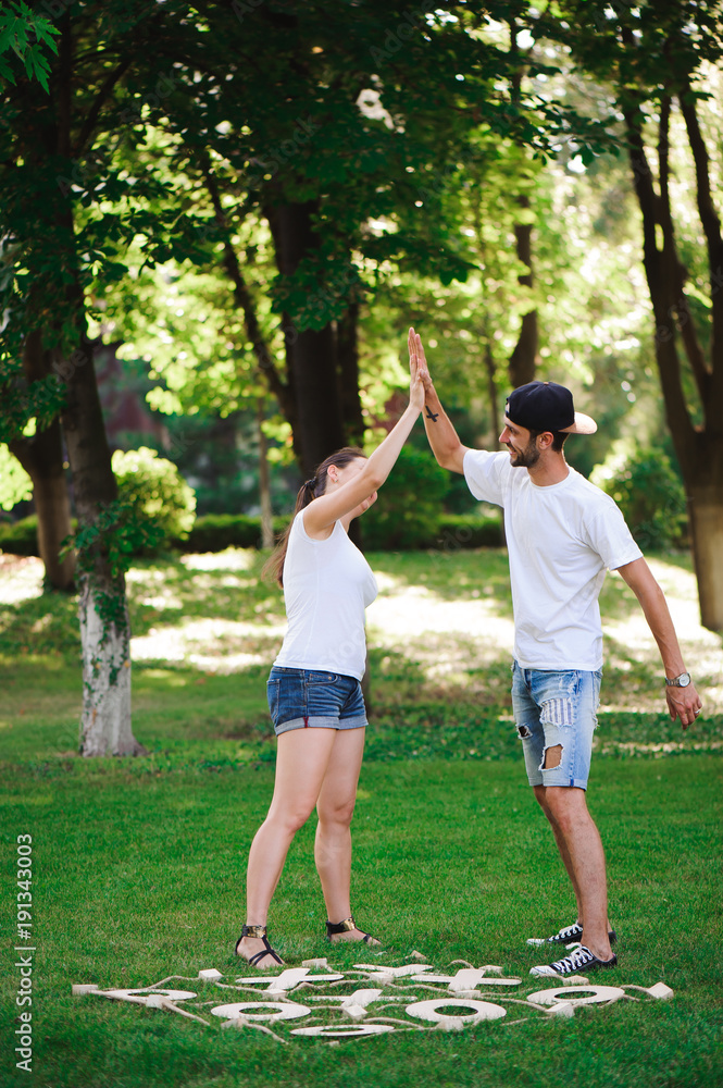 Fototapeta premium A young couple celebrate victory playing tic-tac-toe in the park