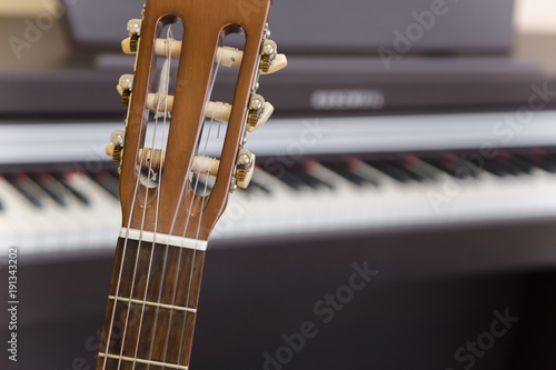 Guitar in front of black wooden piano