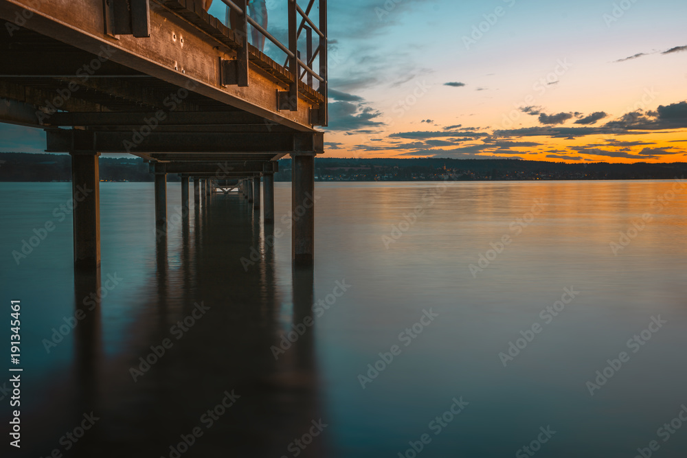 Sunset over the lake of constance with golden shiny bridge