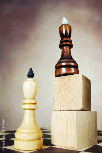 Supremacy. Concept with chess pieces. One chess king has an advantage over another because he stands on a high pedestal photo