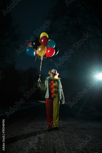 Photo of clown with balls in hands at night photo