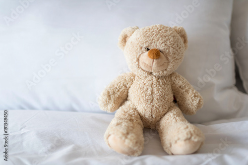 Sleeping teddy bear on white bed